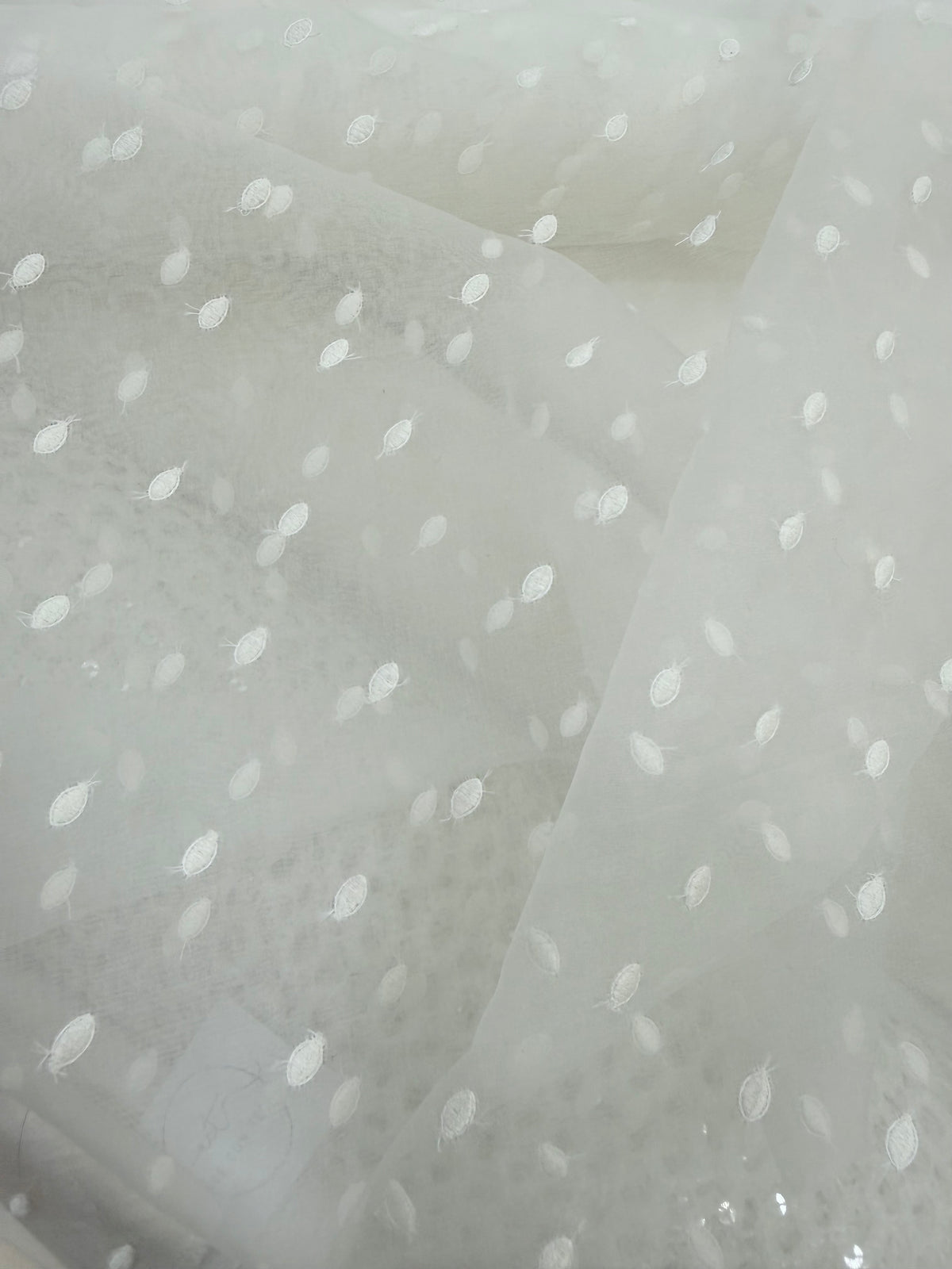 Detalle de la caída de la organza de seda bordada con topos