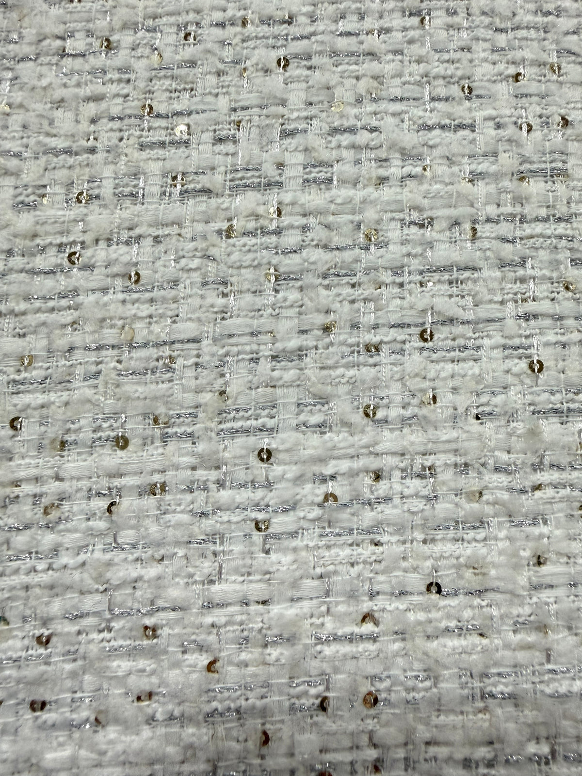 Primer plano del lurex plata y las lentejuelas sobre el tweed blanco
