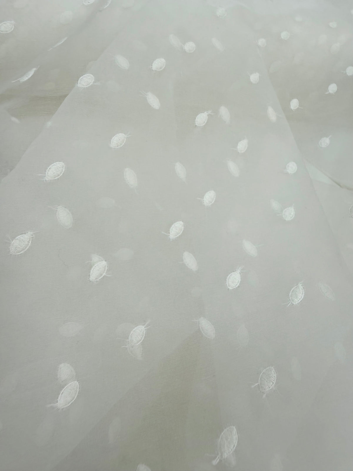 Primer plano de la textura de la organza de seda con topos bordados