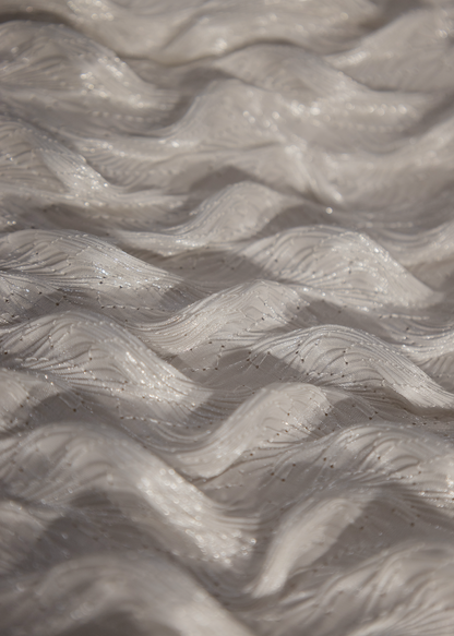 Detalle de tela blanca con textura ondulada en relieve y acabado perlado brillante