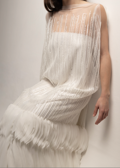 Tela tul con pedrería 3D en diseño editorial, vestido fluido con brillo elegante y líneas verticales.