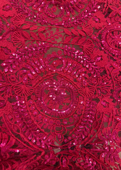 Detalle de tela fucsia con bordado ornamental y brillo