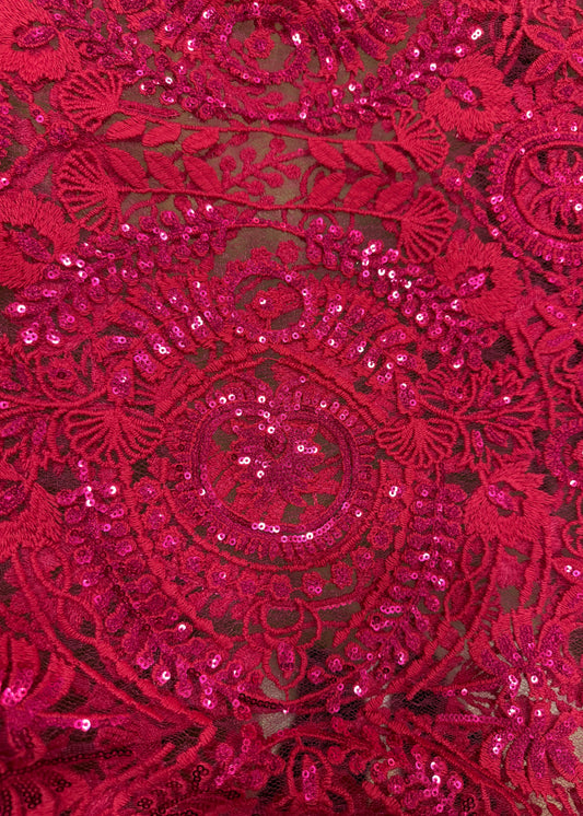 Detalle de tela fucsia con bordado ornamental y brillo