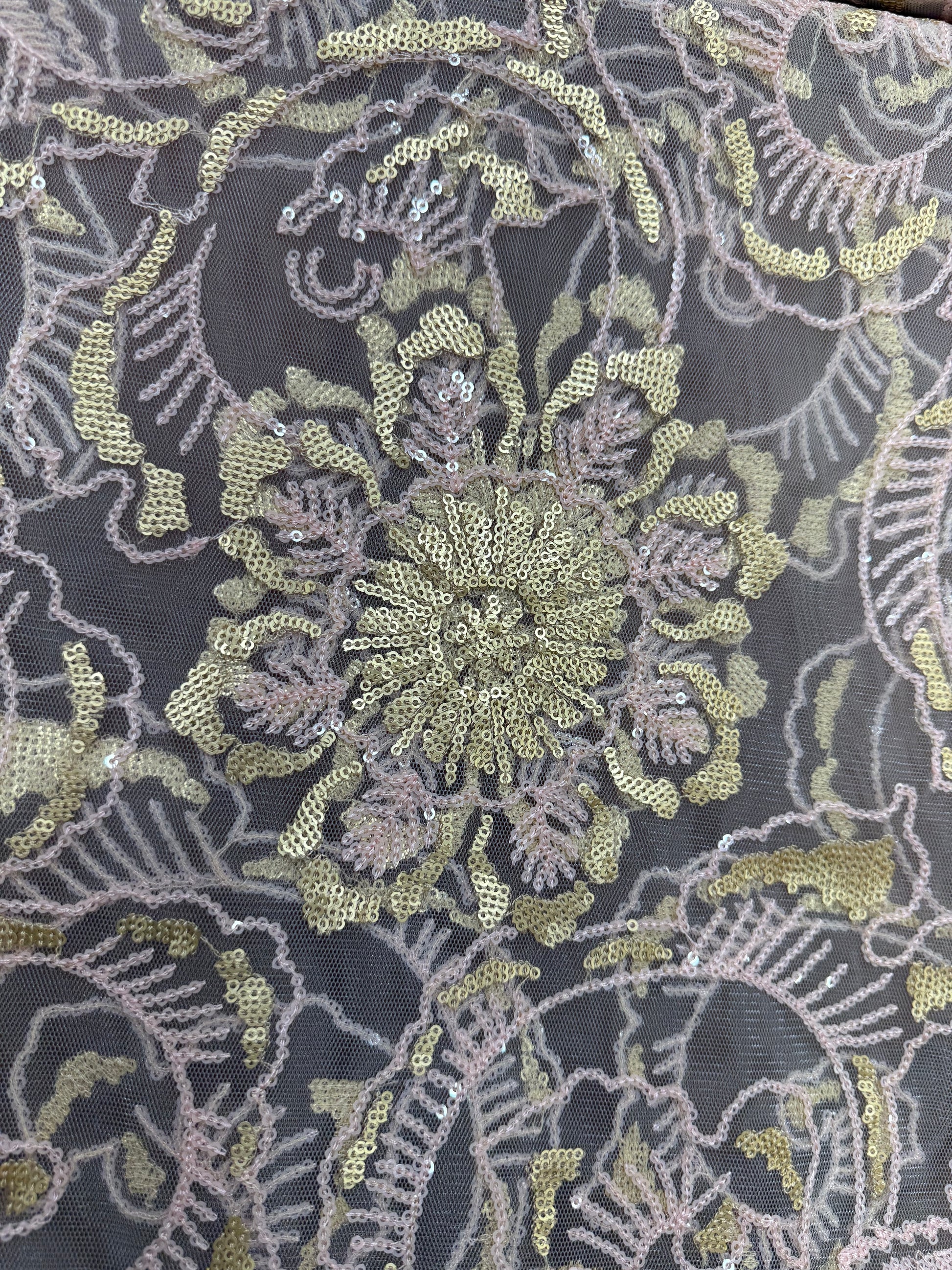 Detalle de bordado floral con lentejuelas en tul rosa y dorado
